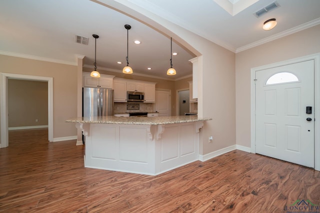 kitchen featuring appliances with stainless steel finishes, decorative light fixtures, white cabinetry, kitchen peninsula, and light hardwood / wood-style flooring