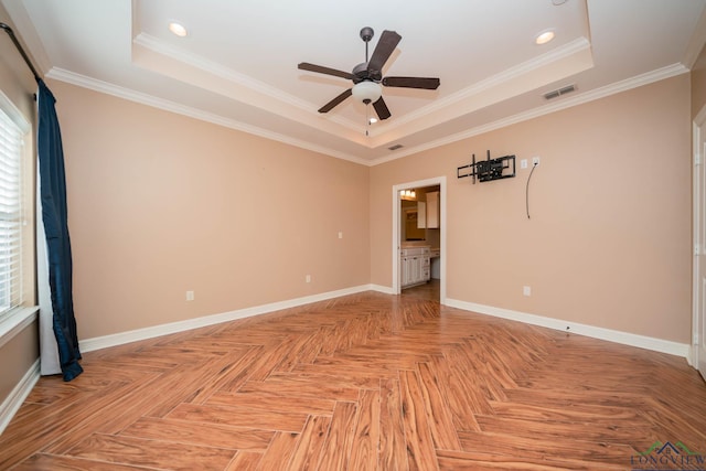 spare room with light parquet floors, crown molding, and a tray ceiling