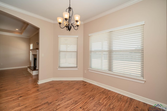 empty room featuring crown molding, hardwood / wood-style floors, and a notable chandelier