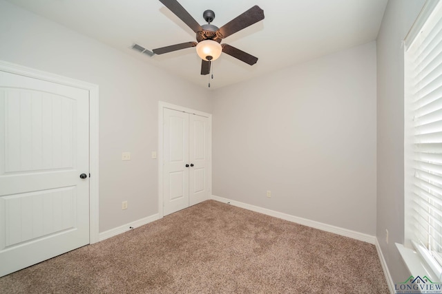 unfurnished bedroom featuring ceiling fan, light colored carpet, and a closet