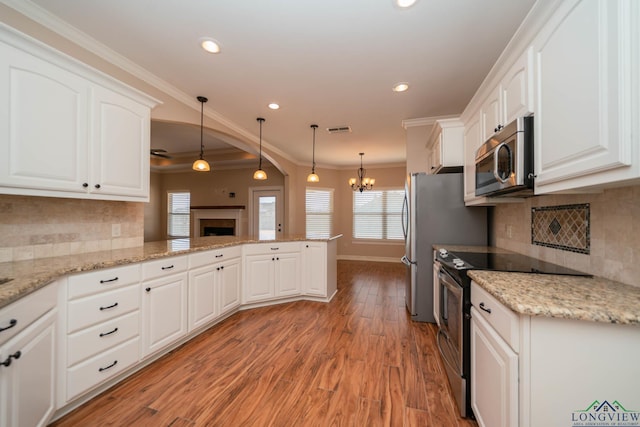 kitchen featuring pendant lighting, stainless steel appliances, kitchen peninsula, and white cabinets