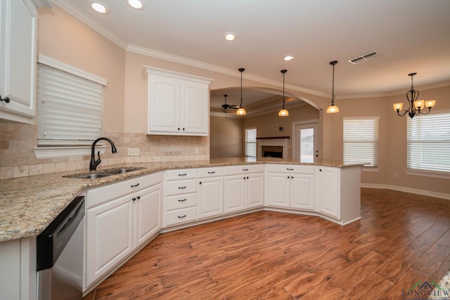 kitchen with sink, dishwasher, hanging light fixtures, white cabinets, and kitchen peninsula