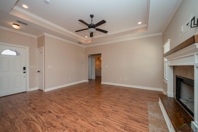 unfurnished living room with a raised ceiling, a healthy amount of sunlight, hardwood / wood-style floors, and a fireplace