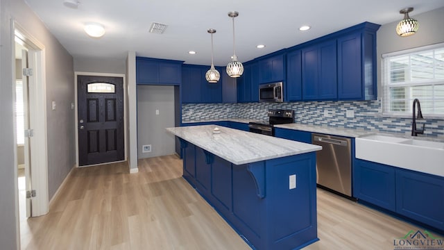 kitchen with hanging light fixtures, a breakfast bar area, light hardwood / wood-style floors, a kitchen island, and stainless steel appliances