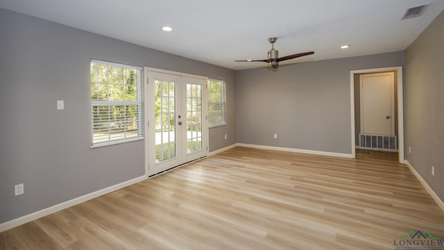 empty room with ceiling fan, light hardwood / wood-style flooring, a wealth of natural light, and french doors