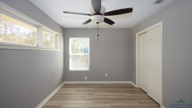 unfurnished bedroom with ceiling fan, light wood-type flooring, and a closet