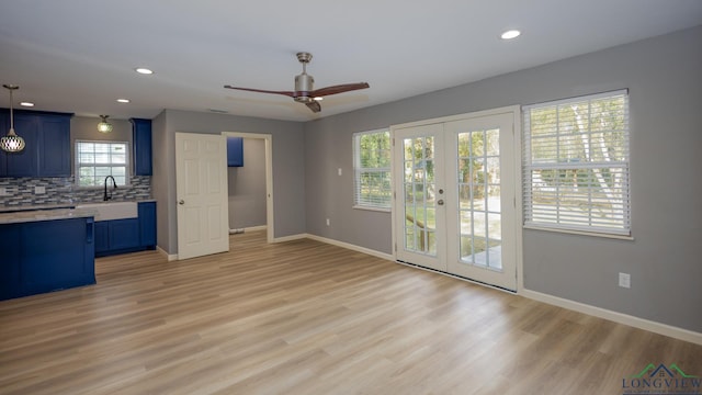 unfurnished living room featuring french doors, light hardwood / wood-style flooring, ceiling fan, and sink