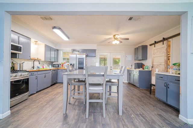 1605 Clearwood Dr, Longview, TX 75604 - kitchen featuring appliances with stainless steel finishes, ceiling fan, a barn door, tasteful backsplash, and gray cabinets