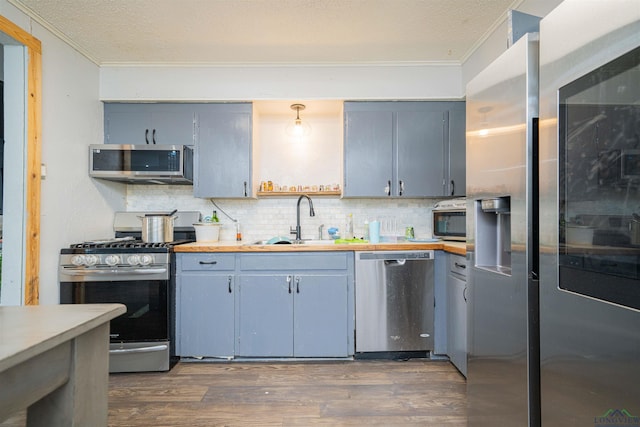 1605 Clearwood Dr, Longview, TX 75604 - kitchen featuring stainless steel appliances, crown molding, tasteful backsplash, dark wood finished floors, and light countertops