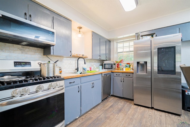 1605 Clearwood Dr, Longview, TX 75604 - kitchen with stainless steel appliances, light wood-style flooring, gray cabinets, decorative backsplash, and crown molding