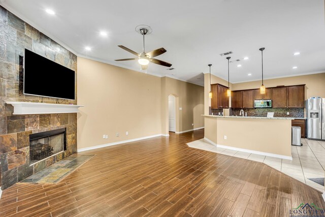 406 Alta St, Longview, TX 75604 - unfurnished living room featuring arched walkways, visible vents, a ceiling fan, a stone fireplace, and ornamental molding