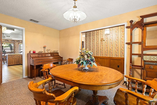 1205 Tiffany Ln, Longview, TX 75604 - dining room featuring a textured ceiling, a wainscoted wall, a chandelier, wallpapered walls, and light colored carpet