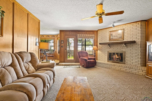 1205 Tiffany Ln, Longview, TX 75604 - carpeted living area featuring plenty of natural light, a fireplace, wooden walls, a ceiling fan, and a textured ceiling
