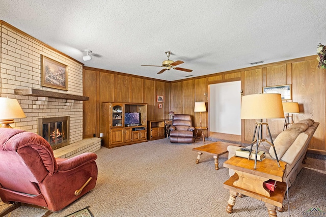1205 Tiffany Ln, Longview, TX 75604 - living area featuring wooden walls, ceiling fan, a textured ceiling, carpet, and a brick fireplace