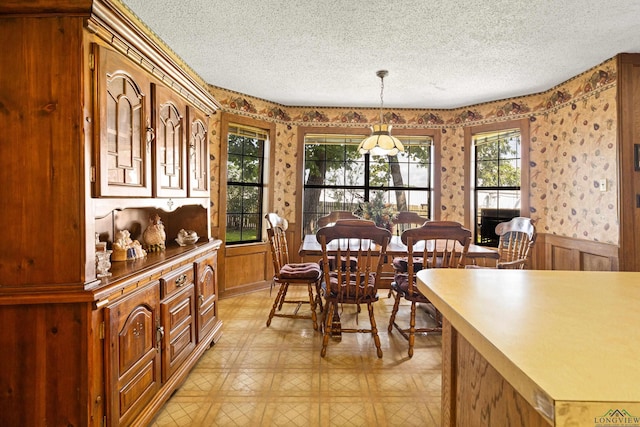 1205 Tiffany Ln, Longview, TX 75604 - dining area with a textured ceiling, wallpapered walls, a wainscoted wall, and light flooring