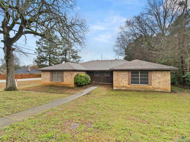 ranch-style home featuring a front lawn, fence, and brick siding