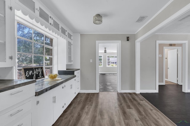 1207 Lettie St, Longview, TX 75601 - kitchen featuring dark countertops, white cabinets, dark wood-style floors, glass insert cabinets, and crown molding