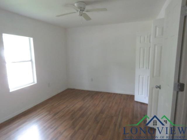 empty room with ceiling fan and dark hardwood / wood-style flooring