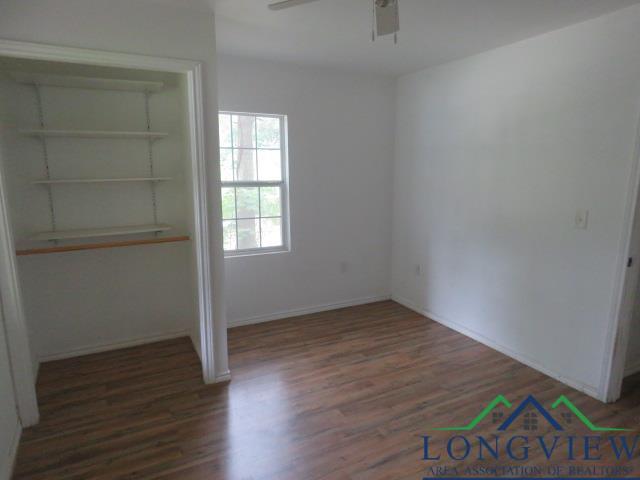 unfurnished bedroom featuring a closet, dark hardwood / wood-style floors, and ceiling fan