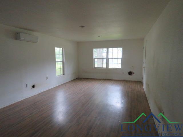 unfurnished room with plenty of natural light, dark hardwood / wood-style floors, and a wall mounted AC