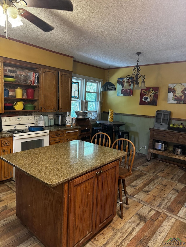 kitchen with a breakfast bar, ceiling fan with notable chandelier, hanging light fixtures, a textured ceiling, and white range with electric stovetop