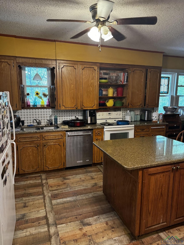 kitchen with dark hardwood / wood-style flooring, white appliances, a textured ceiling, sink, and dark stone countertops