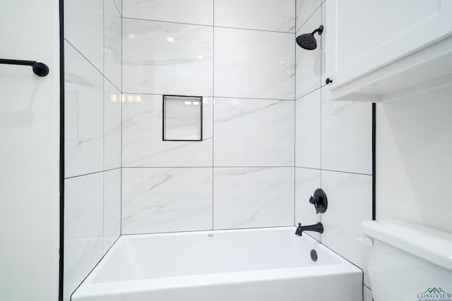 bathroom featuring tiled shower / bath combo and toilet