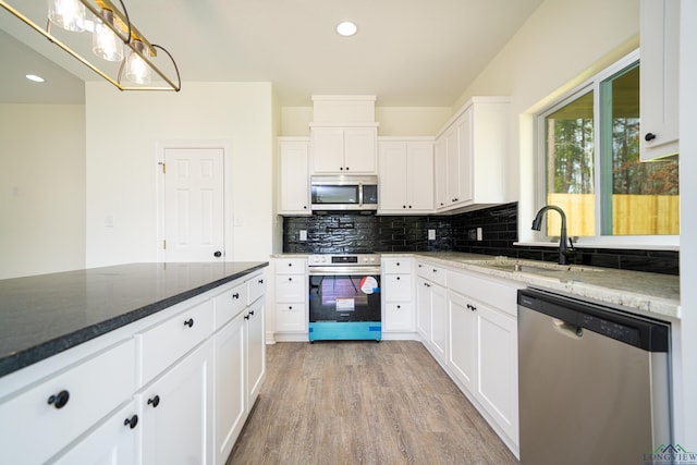 kitchen with dark stone countertops, white cabinetry, sink, and appliances with stainless steel finishes