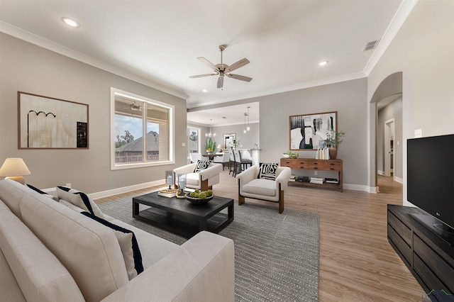 living room with ceiling fan, crown molding, and light hardwood / wood-style floors