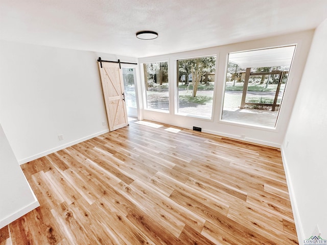 3515 Piping Rock St, Nacogdoches, TX 75965 - spare room featuring a barn door, healthy amount of natural light, and light wood-style flooring