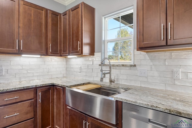 kitchen with stainless steel dishwasher, light stone countertops, sink, and tasteful backsplash