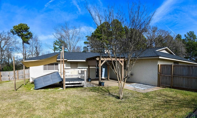 back of property with a wooden deck, a patio area, and a lawn