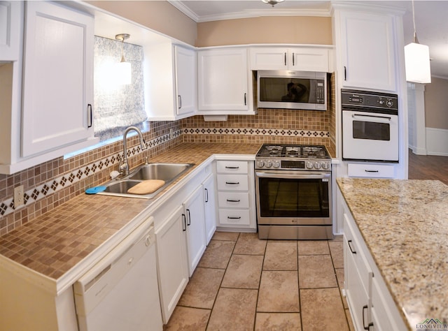 kitchen with sink, appliances with stainless steel finishes, white cabinetry, hanging light fixtures, and backsplash