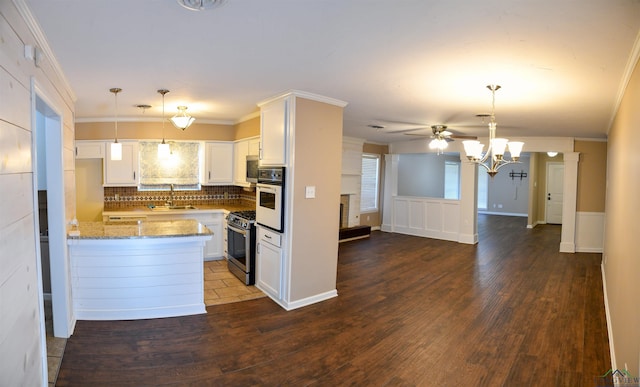 kitchen featuring appliances with stainless steel finishes, pendant lighting, sink, white cabinets, and light stone countertops