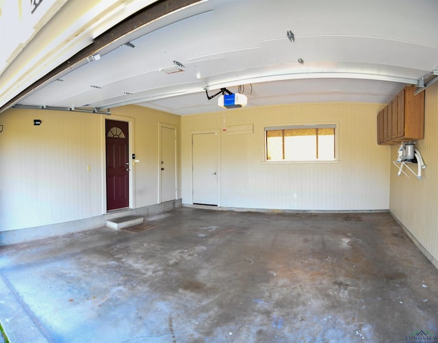 garage with a garage door opener and wood walls