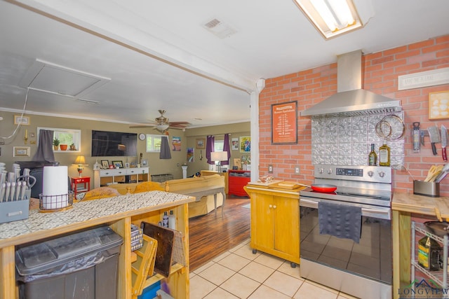 604 Kay Ct, Longview, TX 75601 - kitchen with stainless steel range with electric stovetop, wall chimney exhaust hood, light tile patterned flooring, a ceiling fan, and ornamental molding