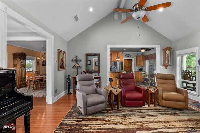 living room with visible vents, a wood stove, a healthy amount of sunlight, a ceiling fan, and light wood-style flooring