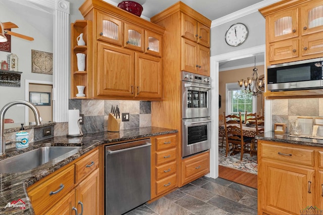 kitchen with a sink, dark stone counters, stainless steel appliances, tasteful backsplash, and ornamental molding