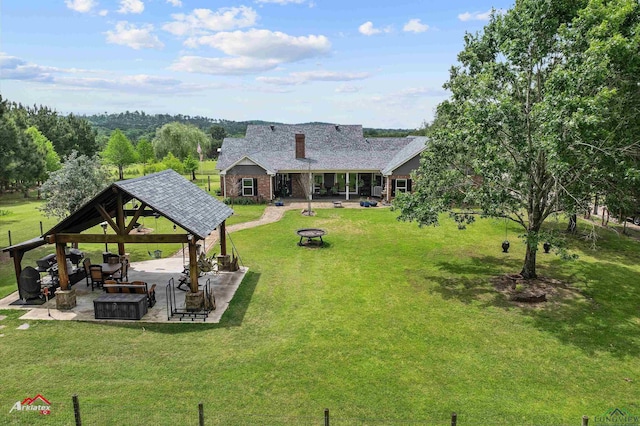 back of property featuring a gazebo, a yard, a fire pit, and a patio area