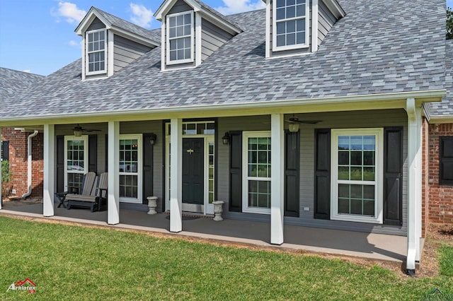 exterior space featuring a yard, brick siding, a ceiling fan, and a porch