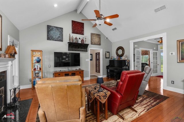 living area with a ceiling fan, visible vents, a high end fireplace, wood finished floors, and high vaulted ceiling