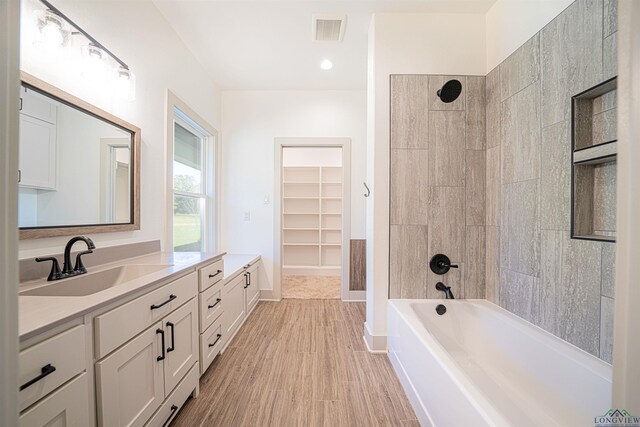 bathroom featuring hardwood / wood-style floors, vanity, and tiled shower / bath