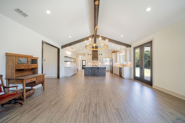 unfurnished living room with sink, french doors, lofted ceiling with beams, a chandelier, and hardwood / wood-style flooring