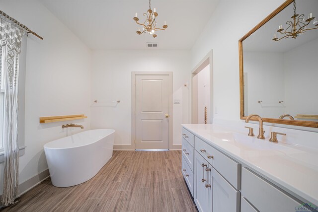 bathroom with a bath, vanity, and a notable chandelier