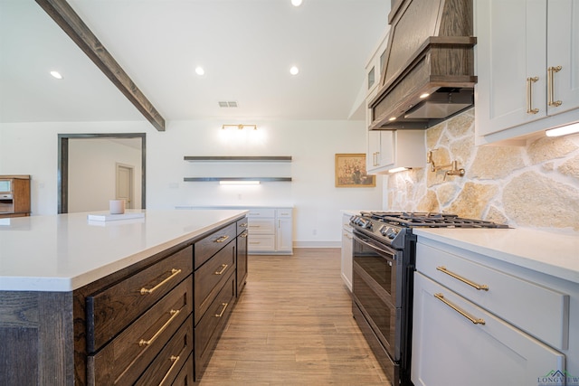 kitchen featuring white cabinetry, beamed ceiling, premium range hood, stainless steel range with gas stovetop, and light wood-type flooring