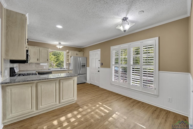 1900 W Hoyt Dr, Longview, TX 75601 - kitchen featuring stainless steel fridge, a textured ceiling, range with gas cooktop, a wainscoted wall, and light wood-style flooring