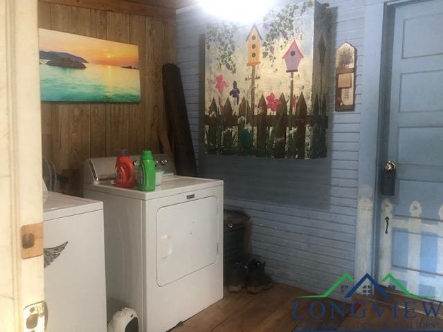 laundry room featuring wooden walls, dark hardwood / wood-style flooring, and washer and dryer