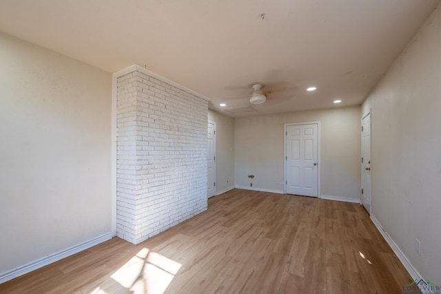 spare room with brick wall, ceiling fan, and light hardwood / wood-style flooring