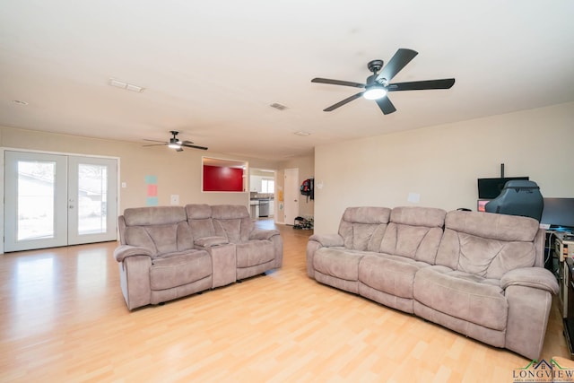 living area with visible vents, french doors, a ceiling fan, and wood finished floors