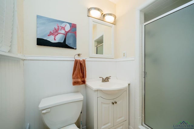 full bathroom with a wainscoted wall, vanity, toilet, and a shower stall